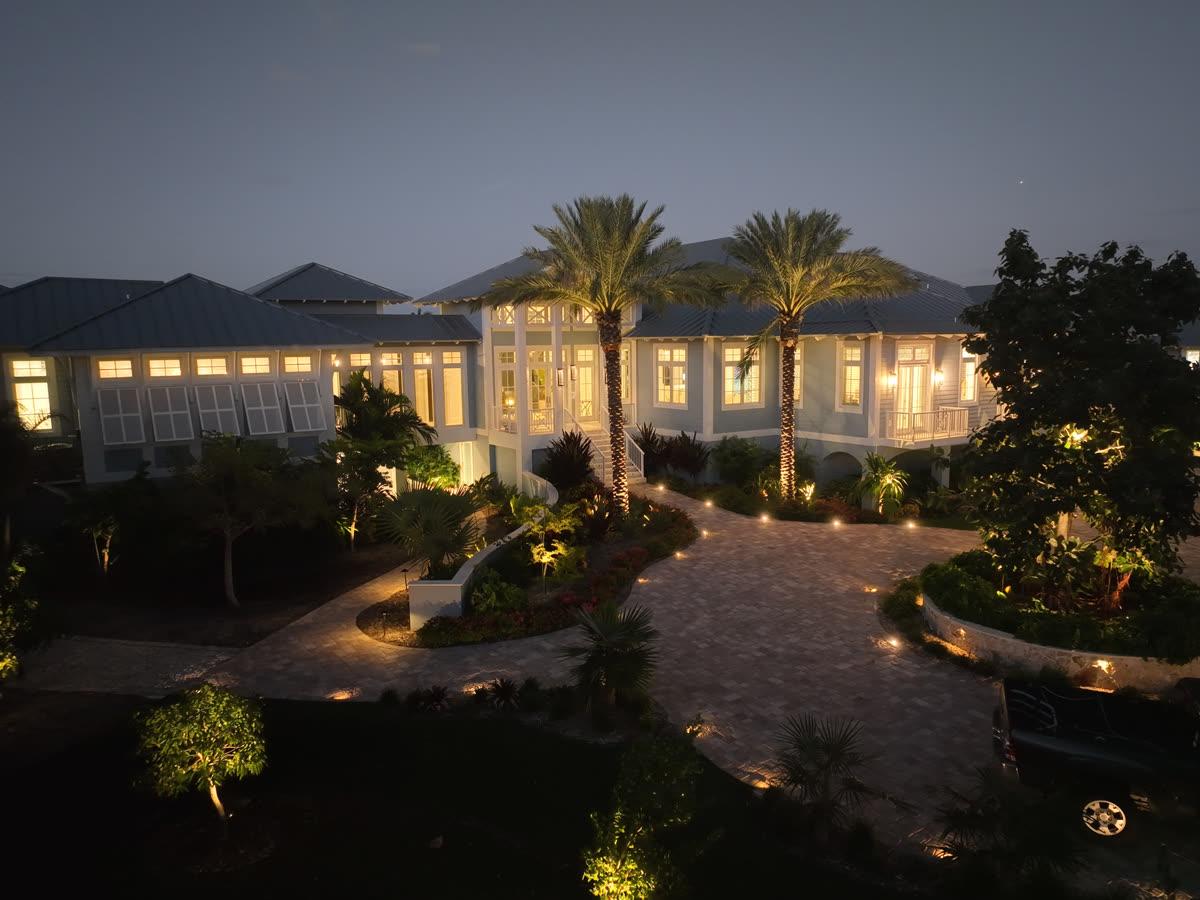 Coastal Source outdoor audio and lighting system installed together along a gulf-front estate landscape at night