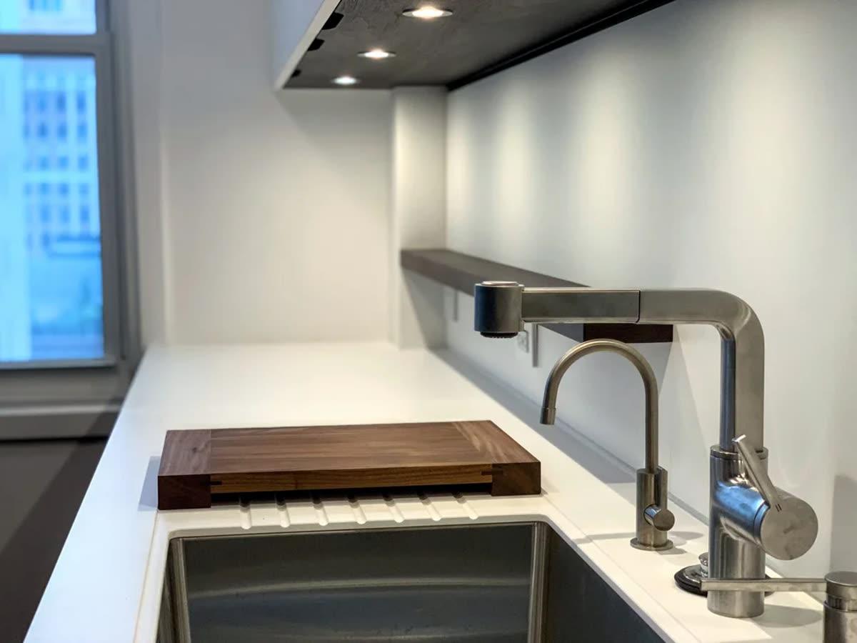 Homework Renovation finished kitchen detail with integrated sink, faucet, counter, and under-cabinet lighting