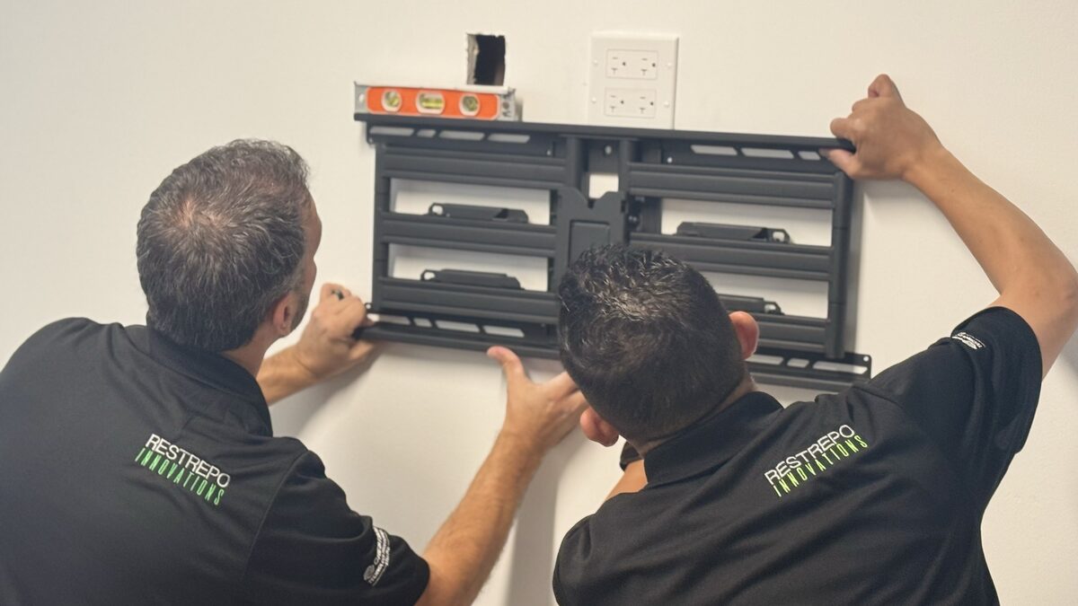Restrepo Innovations technicians mounting a display bracket on a conference room wall