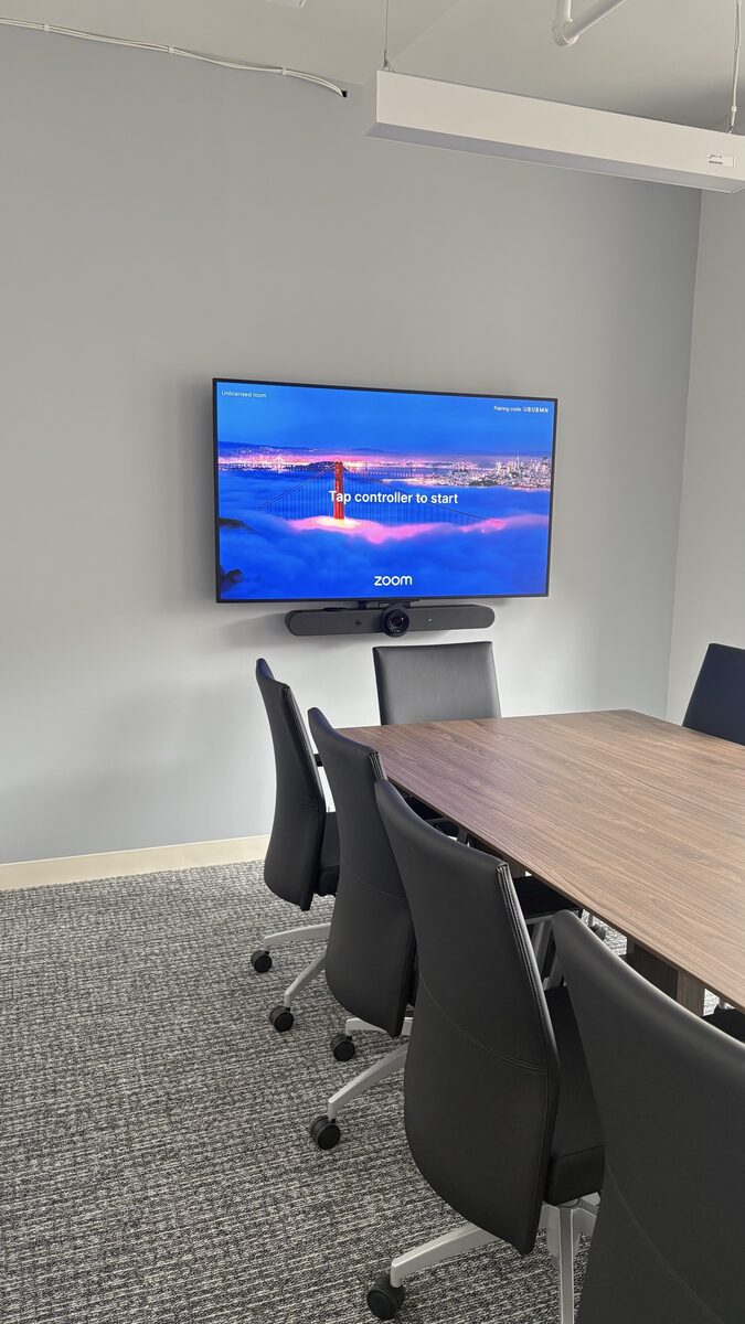 Medium conference room on a Manhattan 9th floor with a 65-inch Samsung display and a Logitech Rally Bar below it