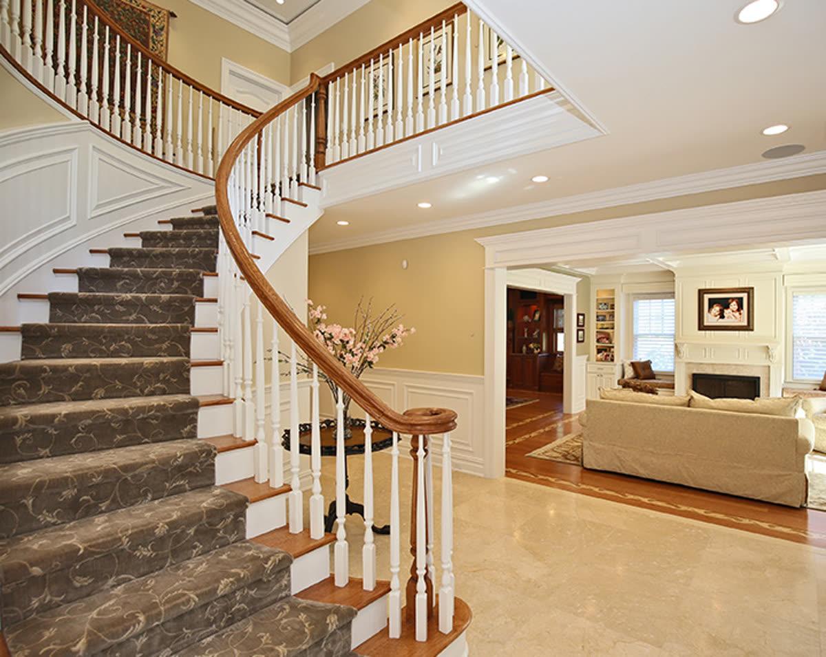 Sinclair Homes custom home builder entryway with a wood door, staircase, and finished hardwood floor