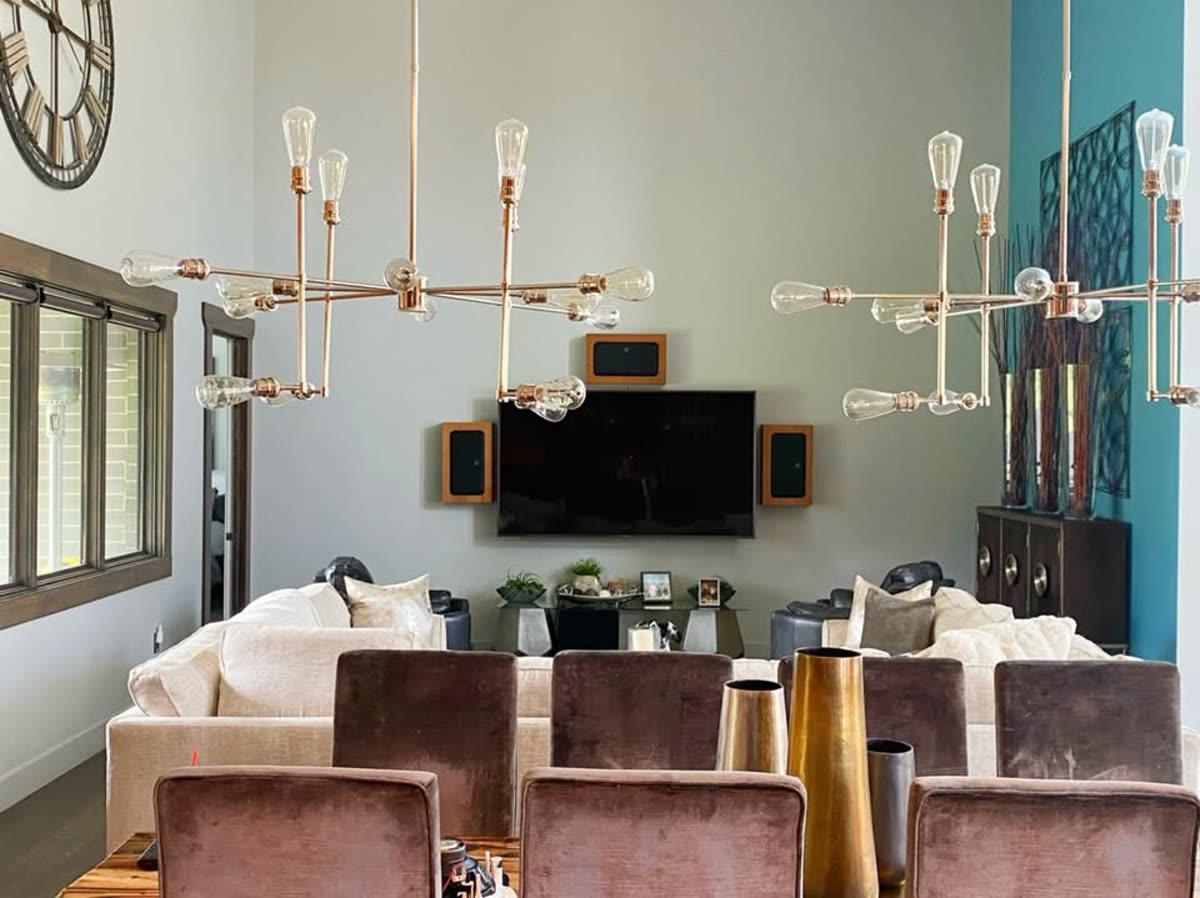 HomeTroniX media room installation with mounted television, orange bookshelf speakers, and Edison-style chandelier in Jonesboro AR