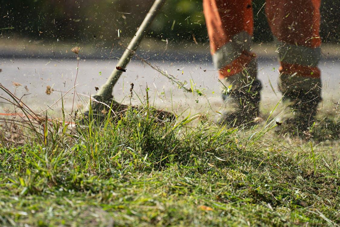 Terracare Landscaping crew member using string trimmer on-site managing grass and transitions between planting areas and hardscape in Northern New Jersey